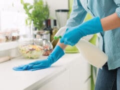 Woman cleaning with a spray detergent Woman cleaning and polishing the kitchen worktop with a spray detergent, housekeeping and hygiene concept